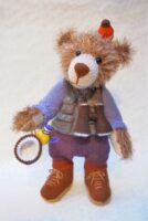 teddy bear knitted toy with glasses and boots looking for birds