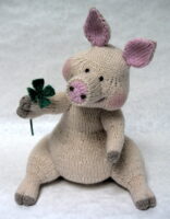 knitted toy of a pig holding a four leaf clover