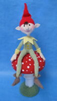 knitted toy of a piskie sat on a toadstool