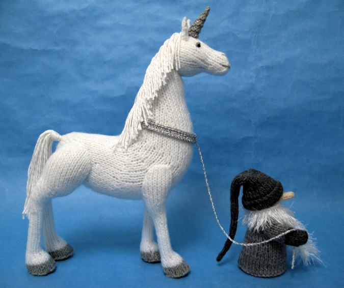 knitted toys of a unicorn led by a small troll