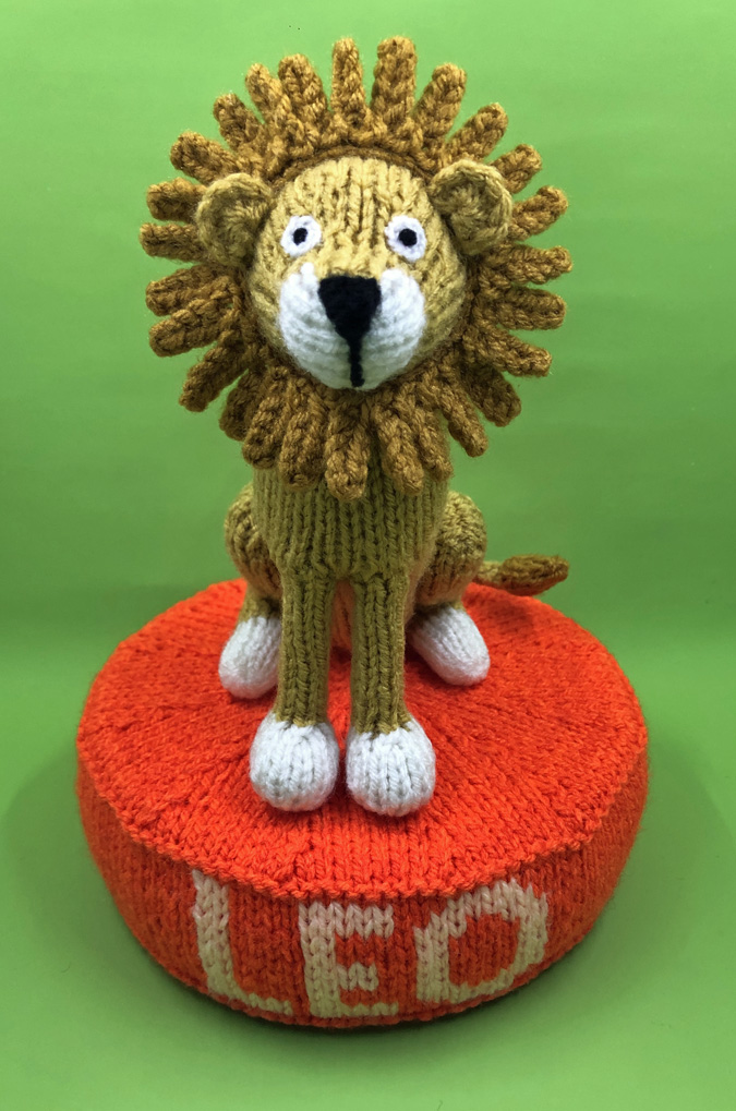 knitted toy of a lion with Leo written on the base