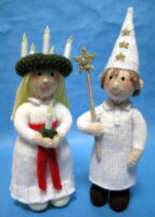 knitted toy of a girl with candles in her hat and boy with stars on his hat both dressed in white