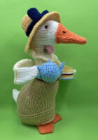 knitted toy of a well dressed duck with tea pot and cake