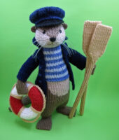 knitted toy of an otter dressed as a river boatman with oars