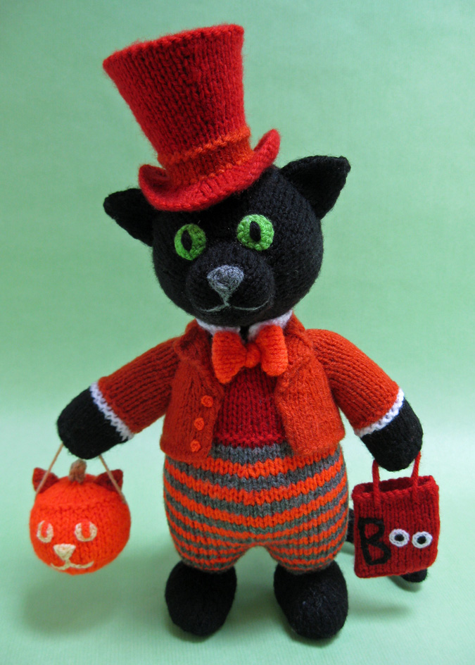 knitted toy of a black cat in a red top hat and tails