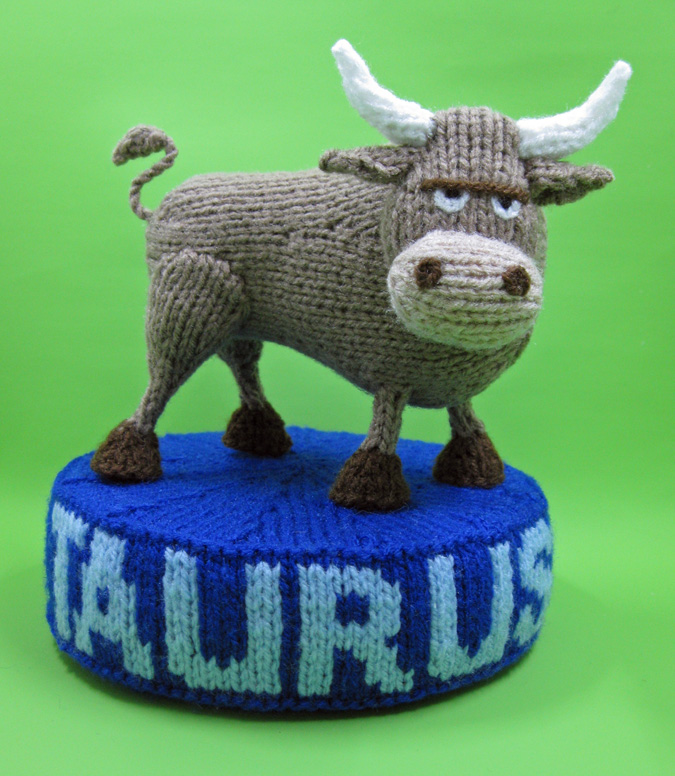 knitted toy of a bull on a plinth with Taurus on it