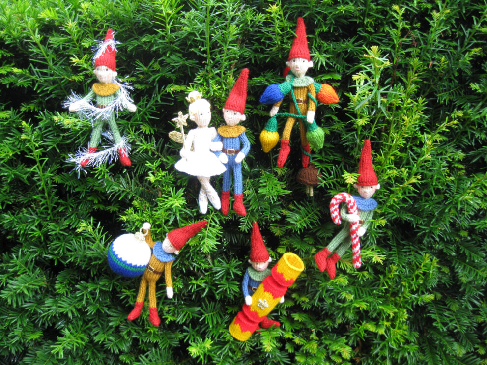 knitted toys of elves trimming a Christmas tree