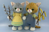 2 knitted toys of kittens holding twigs with catkins on